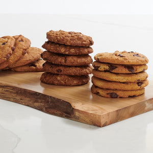 Stacks of chocolate chip, salted caramel and oatmeal raison cookies on wooden platter