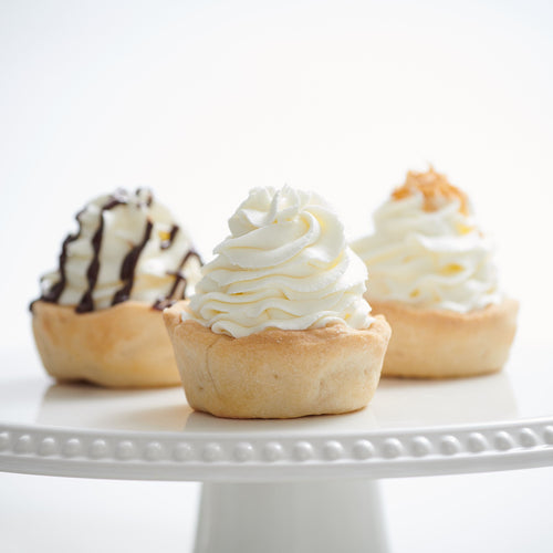 Coconut cream and chocolate cream mini cheesecakes on decorative stand